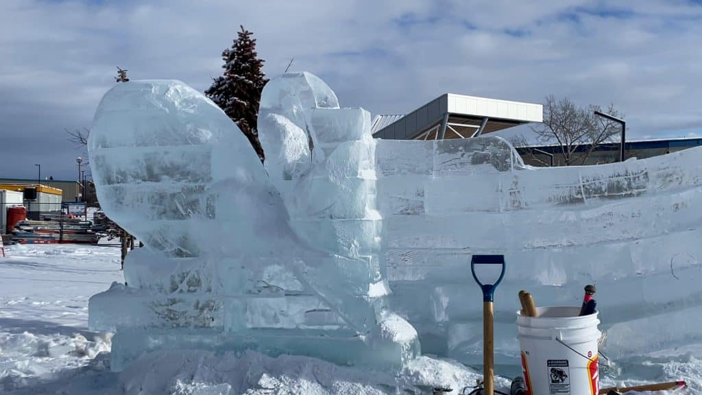 A close up of an ice sculptured Kraken hanging onto the side of a boat.