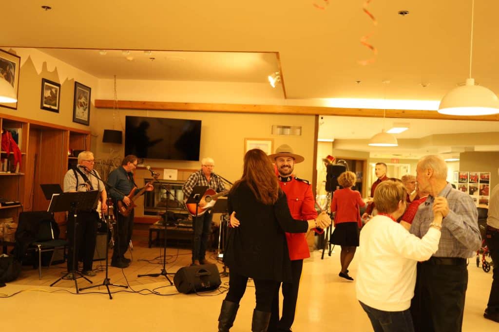 An RCMP officer in a red uniform dancing with a senior woman at a Valentine's Day dance.