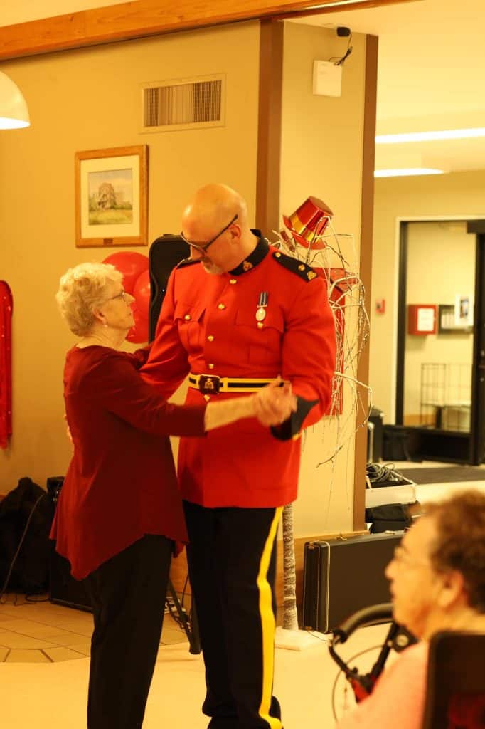 An RCMP officer in a red uniform dancing with a senior woman at a Valentine's Day dance.