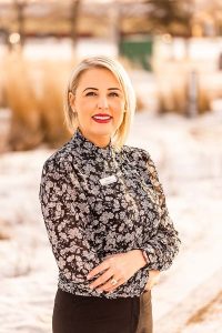 A picture of Shannon Luscombe in a black and white shirt in front of a field.