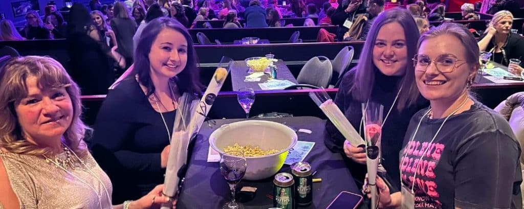 Four ladies sitting at a table holding the flowers they received.