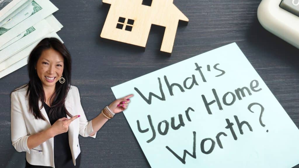 Person in white blazer pointing at sign that says "What's Your Home Worth?"