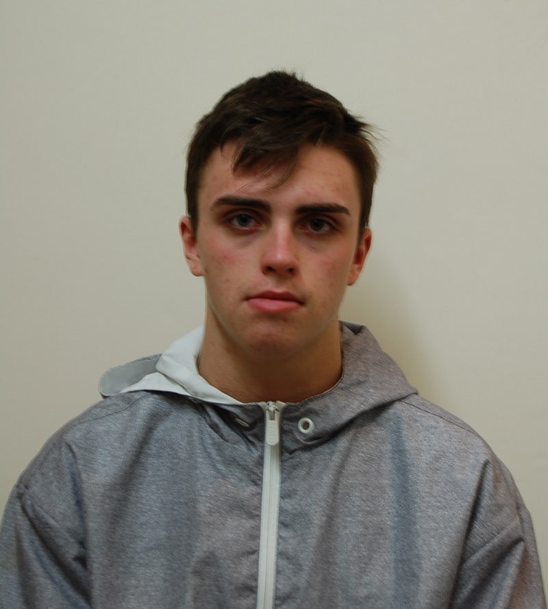 A picture of a young man in a grey jacket in front of a light background.