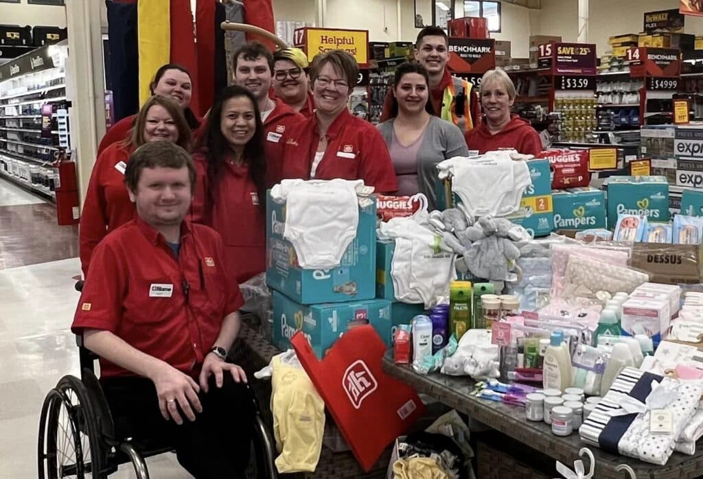 Home Hardware and Community Bridge employees by a pile of baby items.
