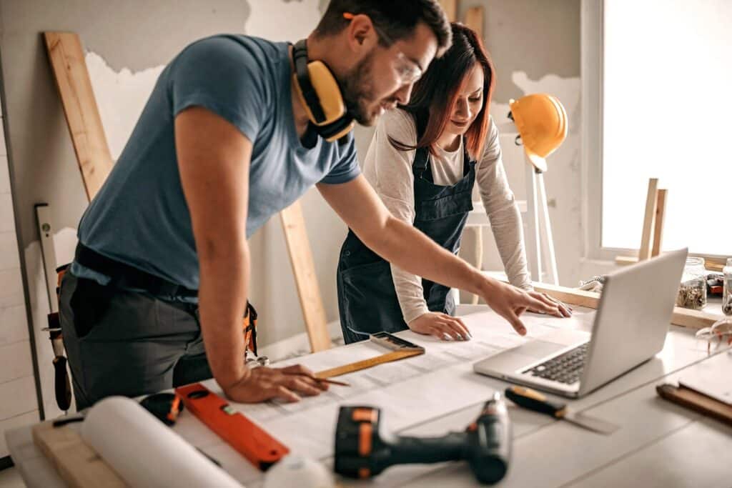 Two people on a construction site looking at a laptop