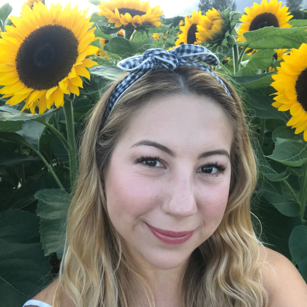 A person in a sunflower field smiling at the camera